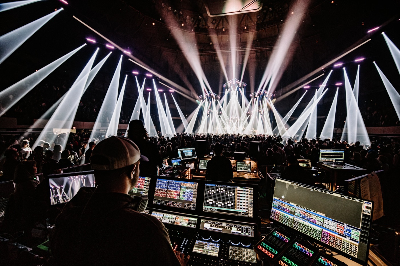 Production lighting director at console — large-scale arena concert with dramatic beam lighting